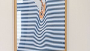 A framed artwork with a striped pattern and a boat.