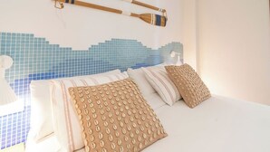 Une chambre à coucher avec un lit, des oreillers et un mur orné d’un motif en mosaïque bleue.