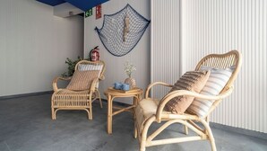 Een kamer met twee rieten stoelen, een tafeltje en een decoratief net aan de muur.