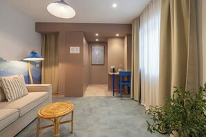 Una sala de estar moderna con un sofá, una mesita redonda, una lámpara y una planta en maceta.