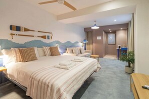 Una habitación de hotel con una cama grande, una zona de estar pequeña, un ventilador de techo y una pared con adornos.