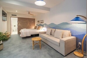 Un dormitorio moderno con cama, sofá, una mesita y un detalle decorativo en la pared.