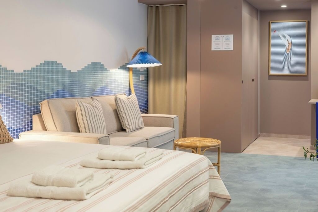 Una habitación de hotel con una cama, un sofá, una mesita y una lámpara.