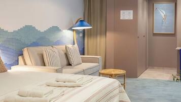 Una habitación de hotel con una cama, un sofá, una mesita y una lámpara.