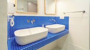 Une salle de bain avec deux lavabos, un mur recouvert de carreaux bleus et deux miroirs.