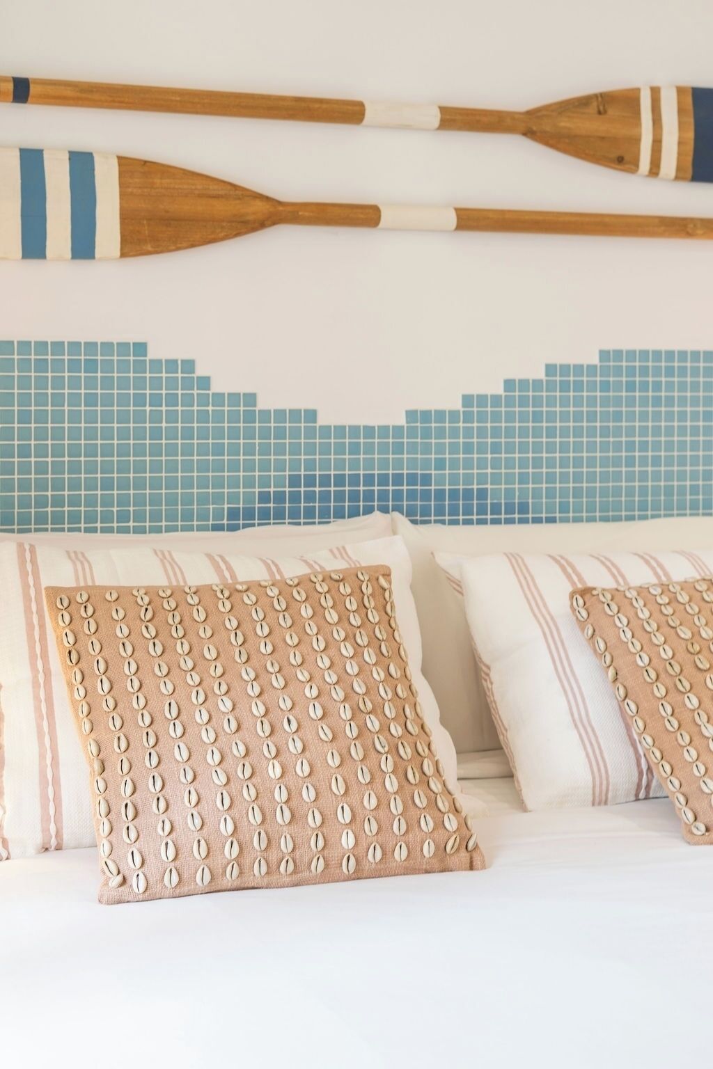 Una cama con almohadas a rayas y una pared de mosaico azul.