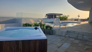 A rooftop pool area with a hot tub, lounge chairs, and a view of the city skyline. - Oceani Cartagena (La Boquilla)