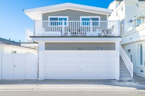 A two-story house with a balcony, a garage, and a 'No Parking' sign. - 3BR Beachfront Home, Patio on the Sand w/ Gorgeous Ocean Views! (Newport Beach)