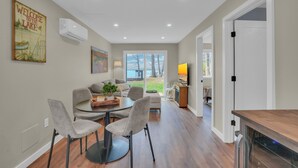 A modern kitchen with a dining area, a large window, and a view of the outdoors. - Lakefront Cottage, Dock, EV Charger, Firepit, Bunkhouse, Family & Pet Friendly (Carp Lake)