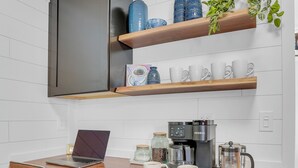 Une cuisine compacte  équipée d’un ordinateur portable, d’une machine à café et de bocaux de rangement.