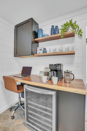 Une cuisine compacte équipée d’un ordinateur portable, d’une machine à café et de bocaux de rangement.