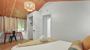 A bedroom with a bed, a desk, and a chair.