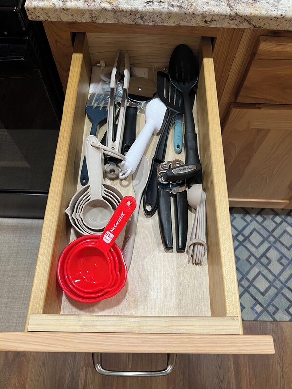 Un cajón de cocina con diversos utensilios y tazas medidoras.