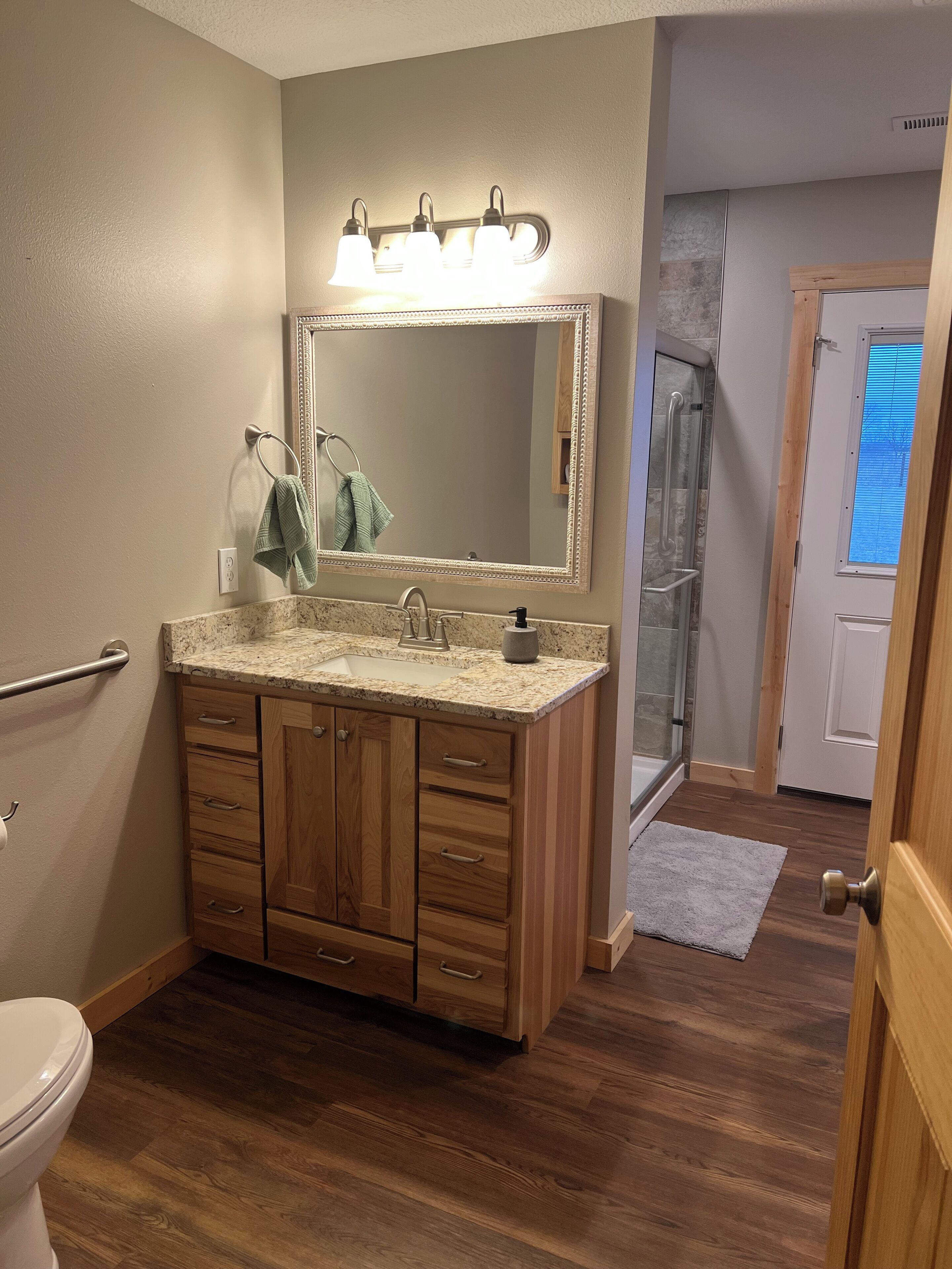 Un baño con tocador de madera, un espejo grande y zona de ducha.