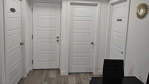 Un couloir avec trois portes blanches, dont une porte sur laquelle est inscrit « buanderie » et une autre sur laquelle est inscrit « machine à laver ».