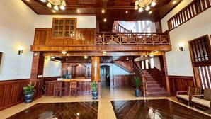 A spacious lobby with a wooden staircase, a reception desk, and a seating area. - SOMA Villa (Siem Reap)