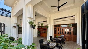 An outdoor patio area with tables and chairs, potted plants, and a wooden door. - SOMA Villa (Siem Reap)