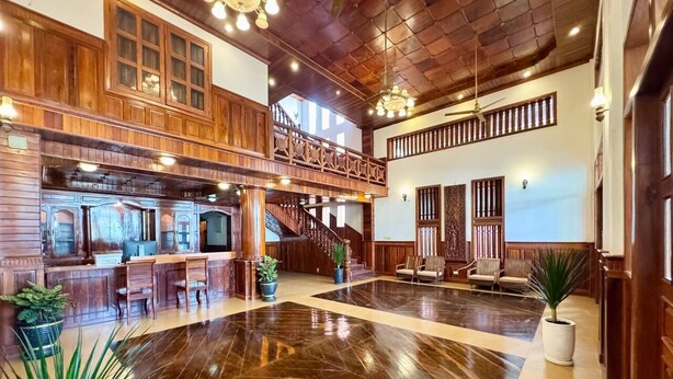 A spacious lobby with a polished wooden floor, a bar area, and a staircase leading to an upper level. - SOMA Villa (Siem Reap)