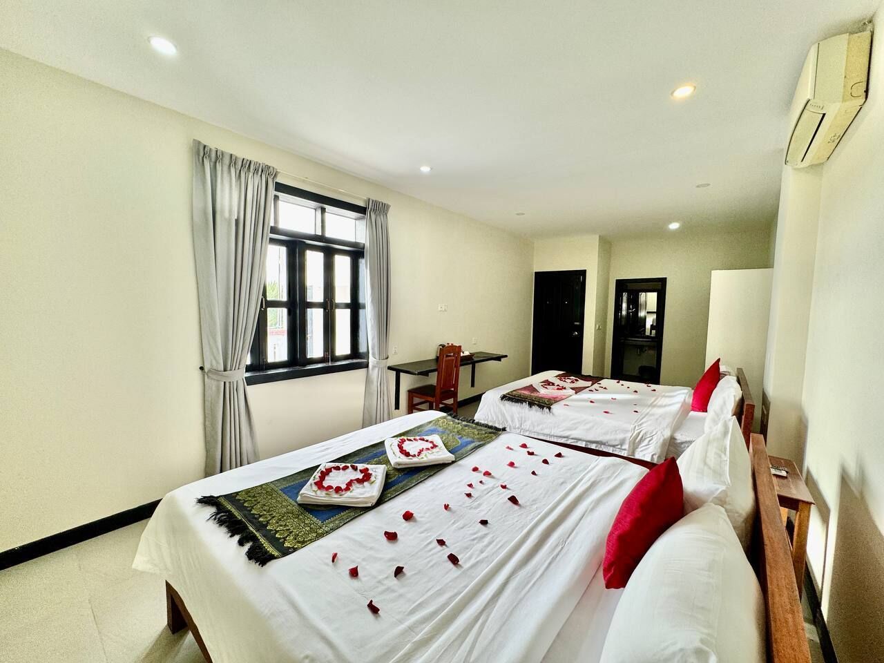 Una habitación de hotel con dos camas, un escritorio y una ventana con cortinas.