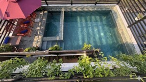 A rooftop pool area with a wooden deck, a red umbrella, and outdoor furniture. - SOMA Villa (Siem Reap)