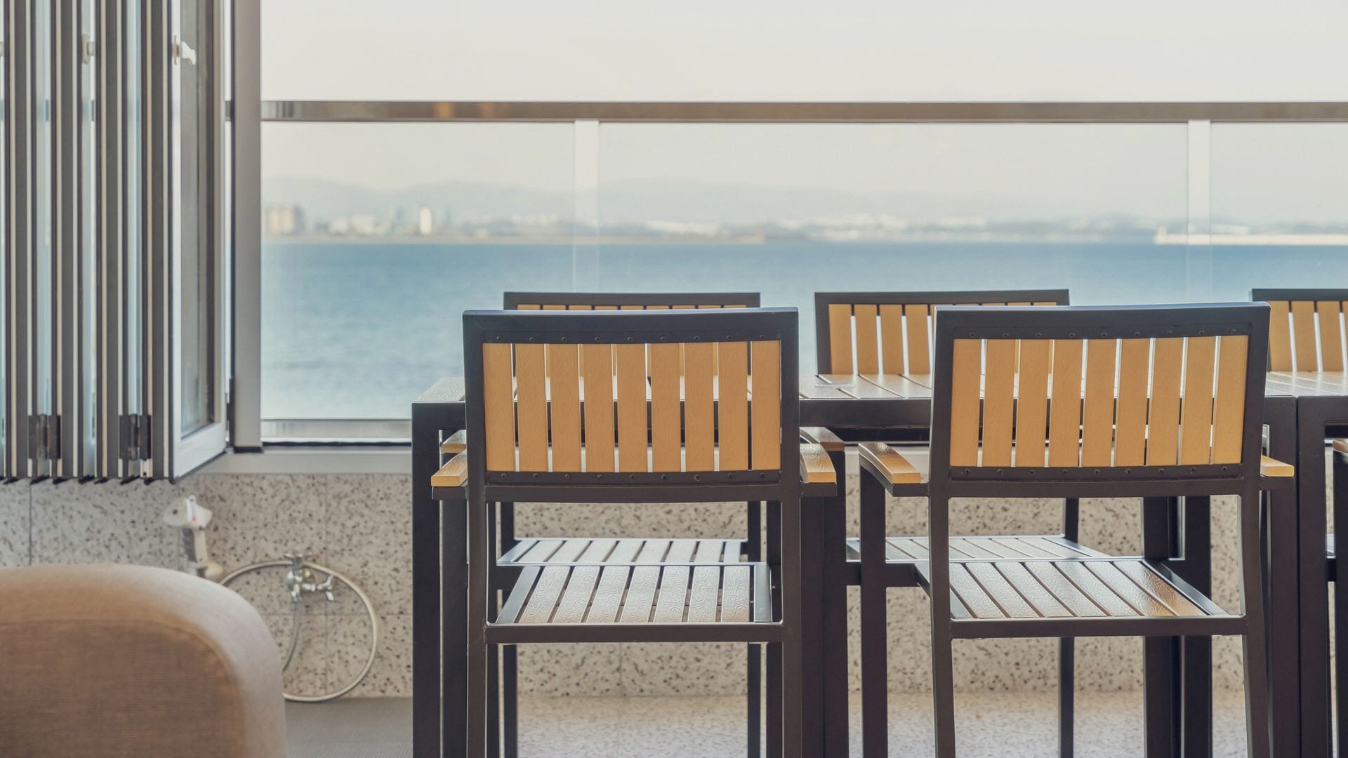 Una terraza con mobiliario exterior, una bicicleta y vista al mar.