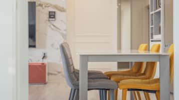 A dining area with a table and chairs, a marble wall, and a bookshelf.