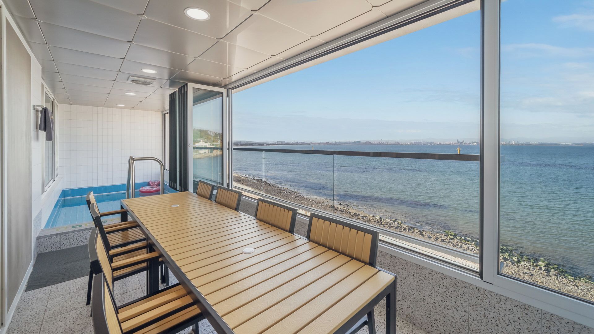 Una sala conferenze moderna con un ampio tavolo e sedie, una zona piscina e vista sull'acqua.