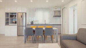 A modern kitchen with a built-in refrigerator, a dining table with chairs, and a sofa in a living area. - Pohang Luna Ocean View Pool Villa (Pohang)