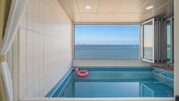 Un baño con un ventanal grande, una bañera y vistas al mar.