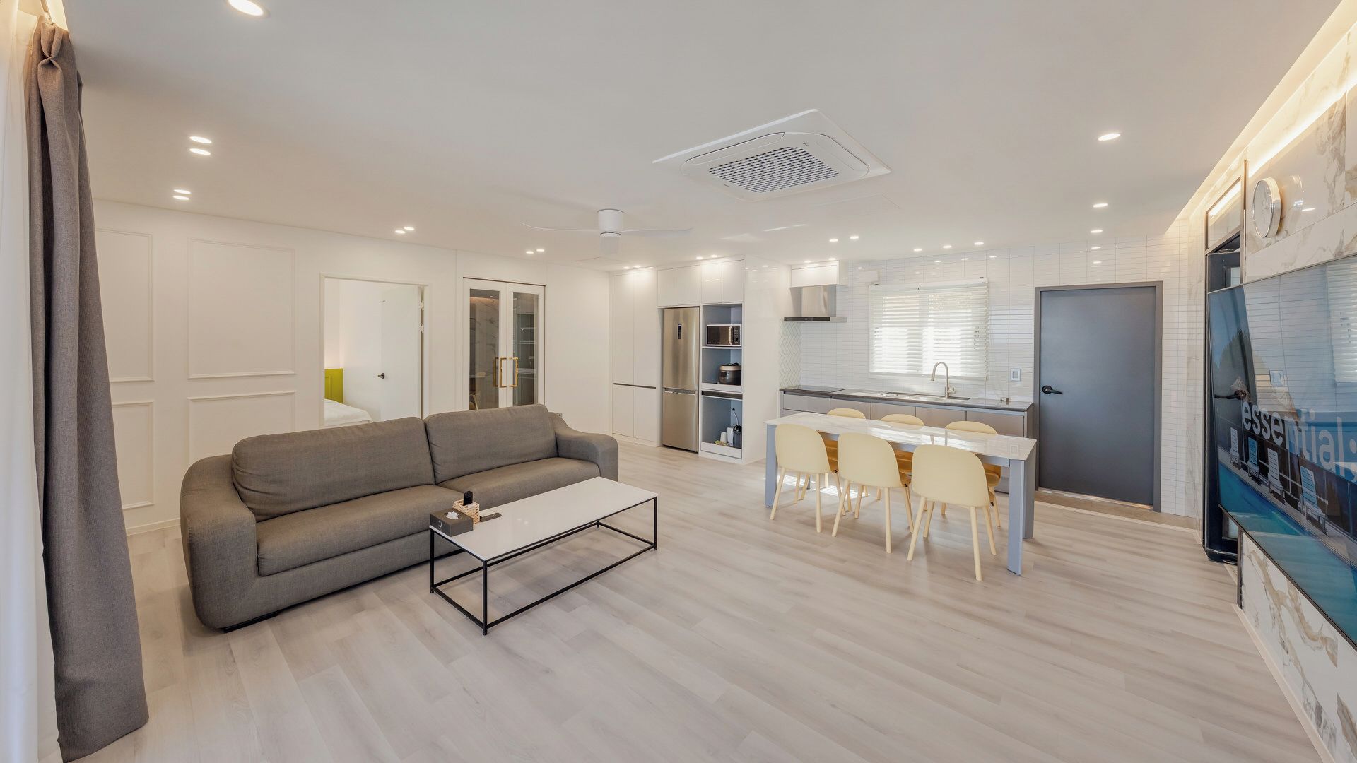 A modern living room with a sofa, coffee table, and dining area with chairs.