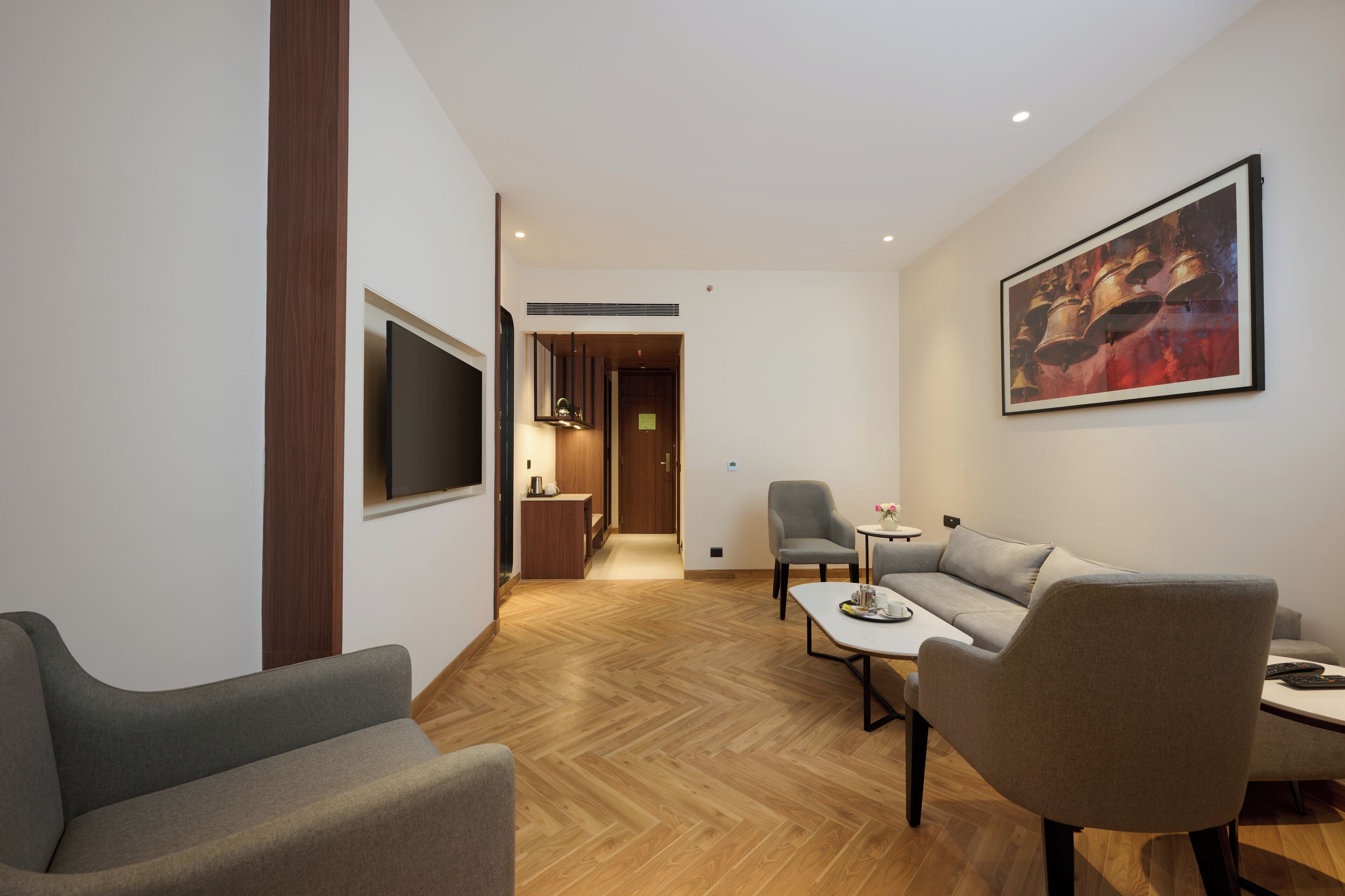 Una sala de estar moderna con un sofá, sillones, una mesa de centro y un televisor de pantalla plana montado en la pared.