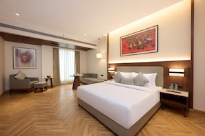 Une chambre d’hôtel avec un grand lit, un canapé, une petite table et un tableau au mur.