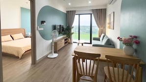 Una sala de estar moderna con comedor, un sofá, un televisor y un ventanal con cortinas.