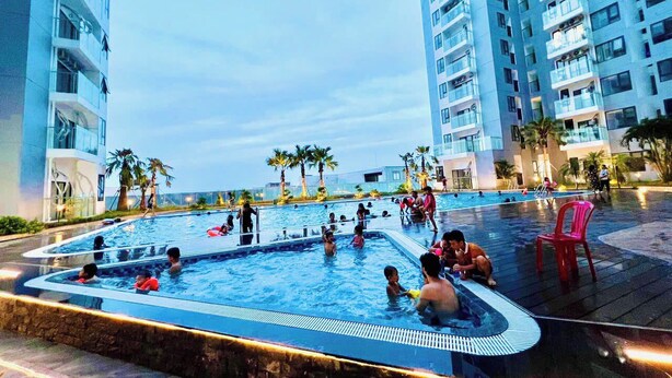 Una piscina rodeada de edificios altos, palmeras y una silla roja.