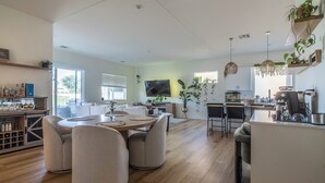 Une cuisine moderne avec un coin repas, un plancher en bois et des luminaires suspendus.