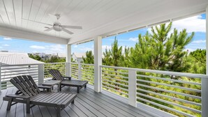 A covered outdoor area with wooden deck, white railings, and a ceiling fan. - Luxury Prominence Home – Pool, Beach & Golf Cart (Inlet Beach)