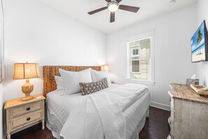 A bedroom with a bed, a nightstand, a lamp, a ceiling fan, a window with blinds, and a painting on the wall. - 30A Coastal Therapy – Pool, Beach & Golf Cart (Inlet Beach)
