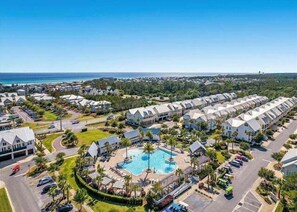 A resort with multiple bungalow-style buildings, a central swimming pool, and a view of the ocean. - 30A Coastal Therapy – Pool, Beach & Golf Cart (Inlet Beach)