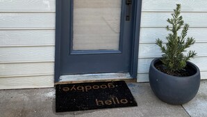 Eine Haustür mit Fensterfeld, eine Fußmatte mit dem Schriftzug "hello" und ein Schild mit "CHICAGO" an der Wand.