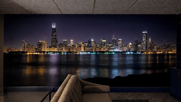 Nachtansicht einer Stadt mit Blick auf das Wasserufer, eine Couch und ein Schrank im Vordergrund.