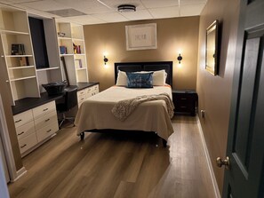 A bedroom with a bed, bedside tables, a desk, and a bookshelf.