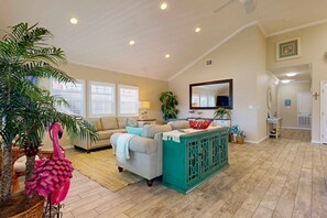 Un salon spacieux avec un canapé beige, un meuble turquoise et un grand miroir.
