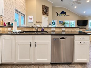 A modern kitchen with white cabinetry, a stainless steel dishwasher, and a ceiling fan. - Private Heated Pool, Pet Friendly, Golf Cart Included (Port Aransas)