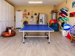 A room with a ping pong table, a horse-shaped inflatable, and various sports equipment. - Private Heated Pool, Pet Friendly, Golf Cart Included (Port Aransas)