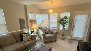 Ein Wohnzimmer mit Sofa, Sessel, Couchtisch und Fernseher.