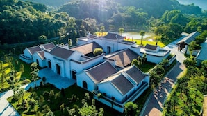 Un conjunto arquitectónico tradicional con varias edificaciones, rodeado de abundante vegetación y un lago.