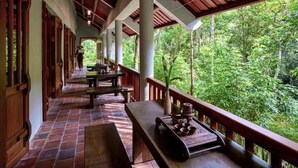 Un espacio al aire libre cubierto con bancos y mesas de madera, rodeado de abundante vegetación.