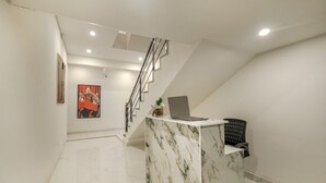 A modern reception area with a marble counter, a laptop, and a staircase. - Aerostays Studio Apartments (Dera Bassi)
