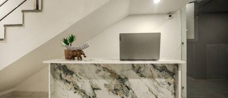 A modern interior with a marble counter, a laptop, and a small elephant figurine.