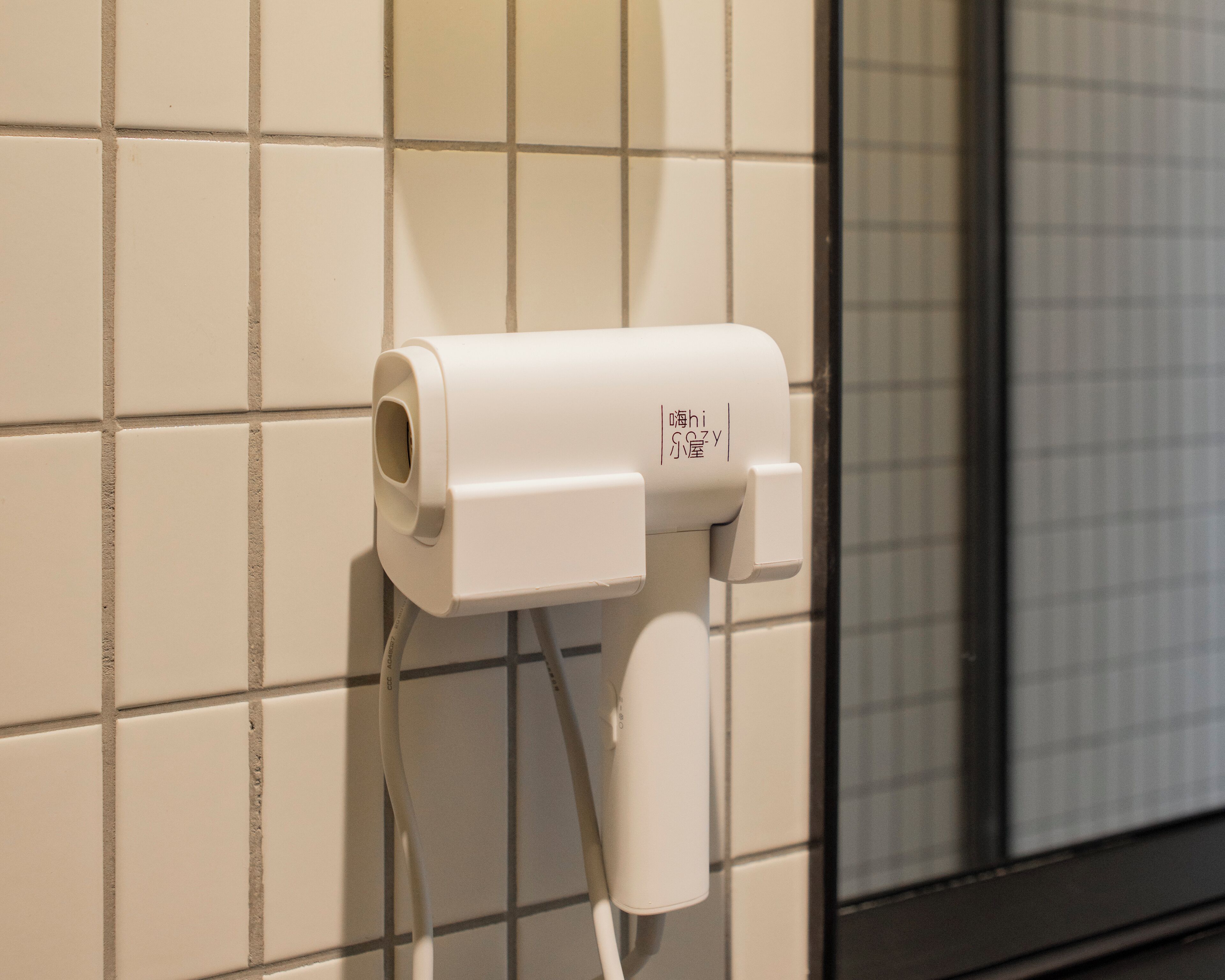 Une prise électrique blanche sur un mur carrelé.